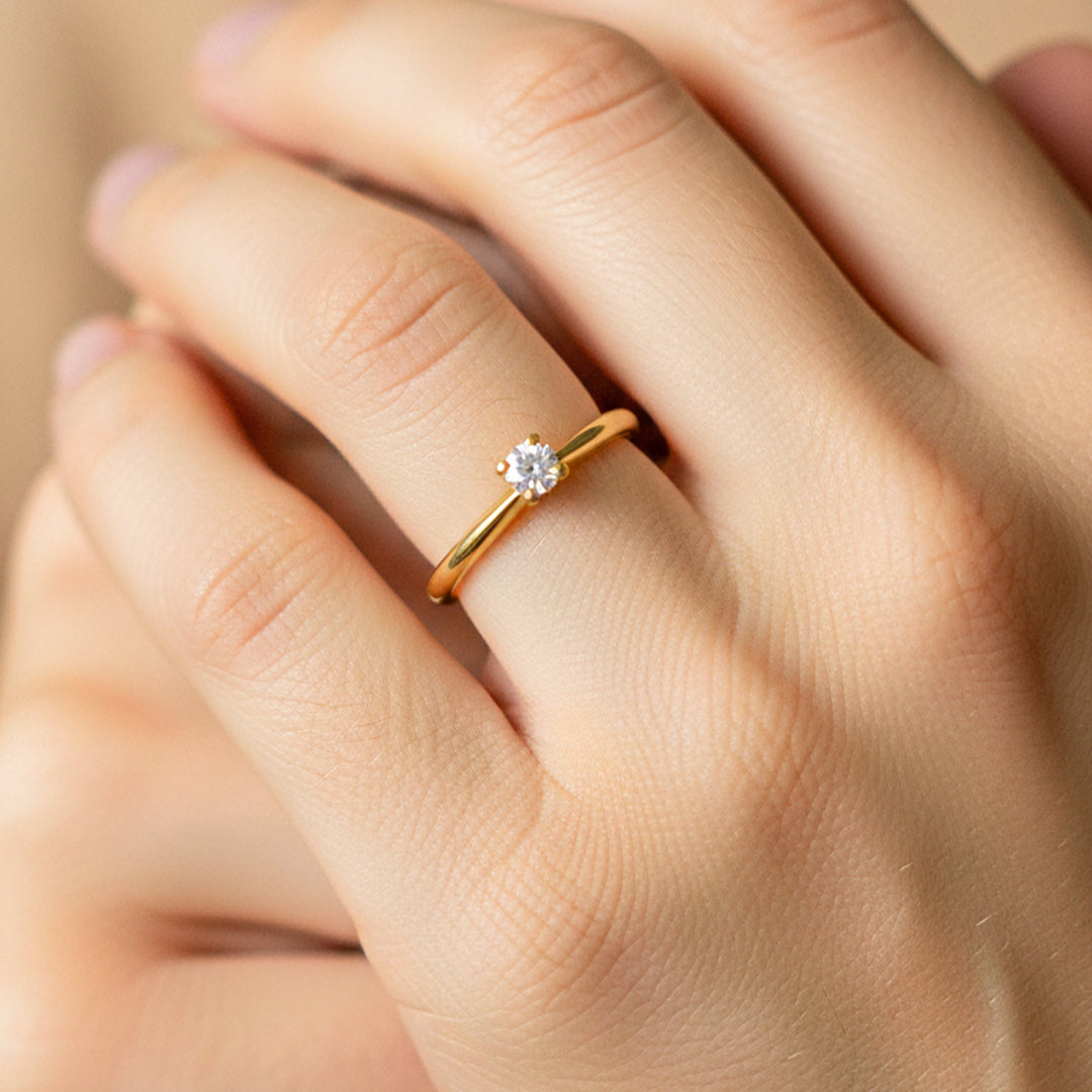 Mano de modelo usando un anillo solitario en oro amarillo de 18 quilates con cristal de Joyería Caracas. 