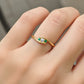 Mano de modelo usando un anillo en oro amarillo con cristales blancos y verde de Joyería Caracas. 