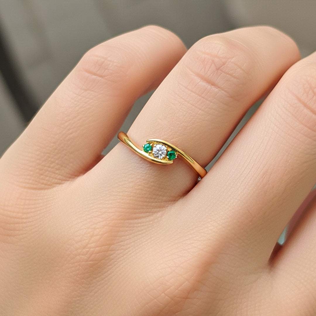 Mano de modelo usando un anillo en oro amarillo con cristales blancos y verde de Joyería Caracas. 