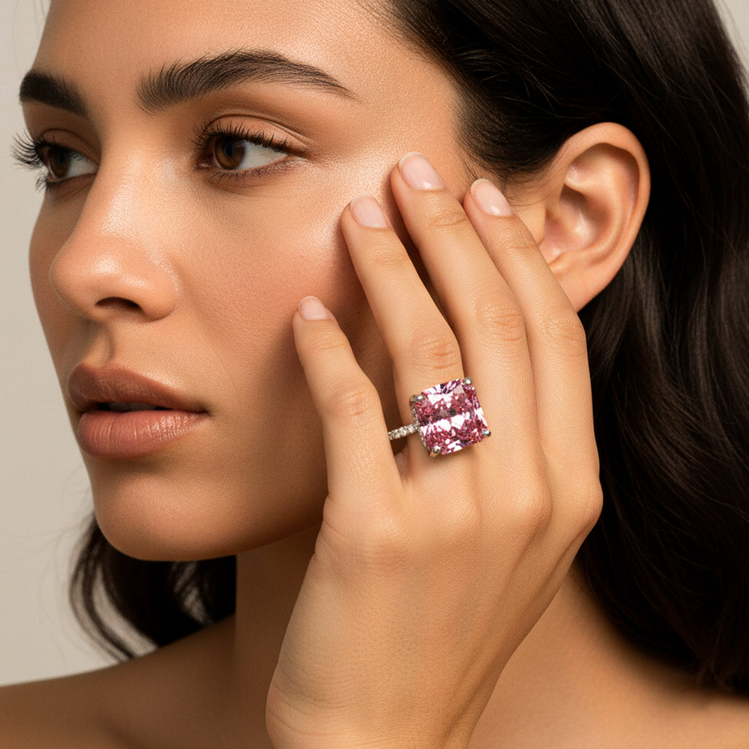 Modelo usando un anillo en oro blanco de 18 quilates con Zafiro (sintético) en tonalidades rosas y anaranjadas ubicado en el centro acompañado de Moissanitas de color blanco alrededor fabricado en Joyería Caracas. 