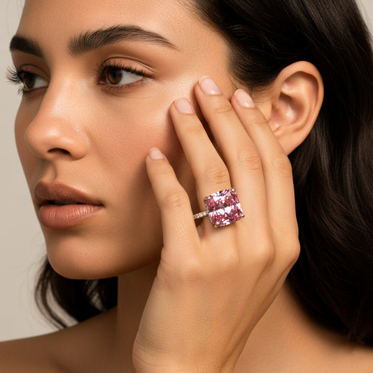 Modelo usando un anillo en oro blanco de 18 quilates con Zafiro (sintético) en tonalidades rosas y anaranjadas ubicado en el centro acompañado de Moissanitas de color blanco alrededor fabricado en Joyería Caracas. 