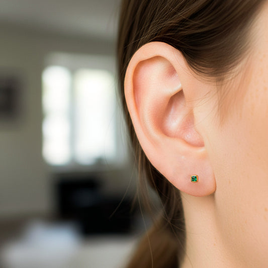 Oreja de modelo usando un topito en oro amarillo de 18 quilates con Esmeralda en corte de princess de Joyería Caracas. 