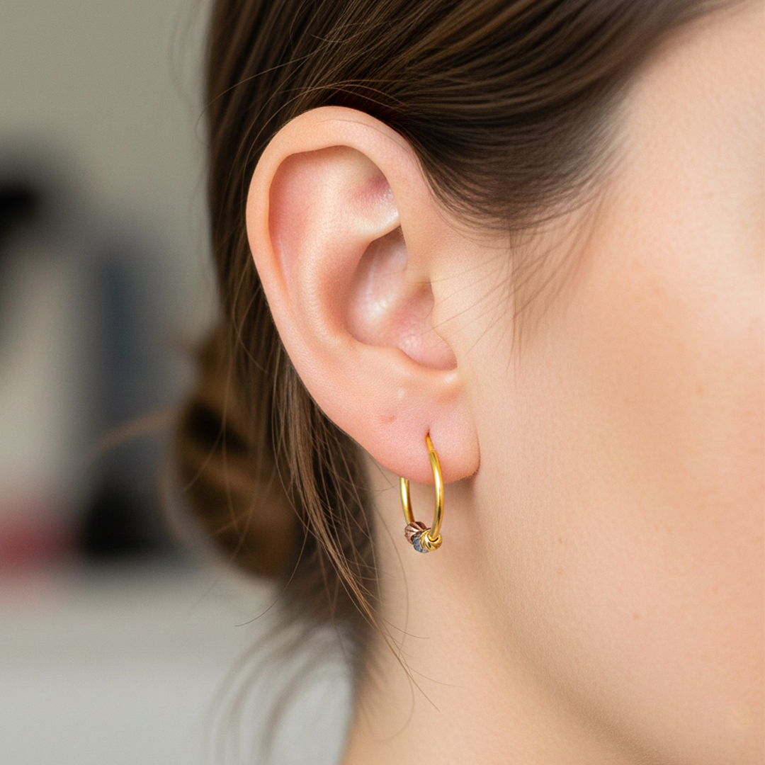 Oreja de modelo usando unas candongas sin fin con esferas 3 oros de 18 quilates de Joyería Caracas. 