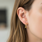 Oreja de modelo usando unos aretes sin fin con esfera en oro amarillo de 18 quilates de Joyería Caracas. 