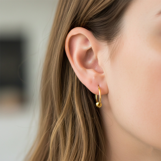 Oreja de modelo usando unos aretes sin fin con esfera en oro amarillo de 18 quilates de Joyería Caracas. 
