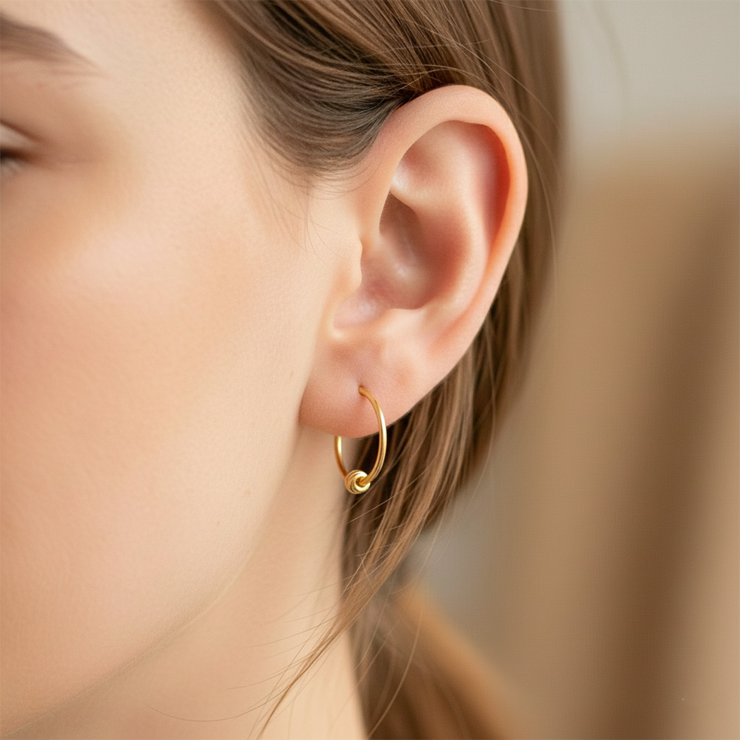 Oreja de modelo usando unos aretes sin fin con esfera en oro amarillo de 18 quilates de Joyería Caracas. 