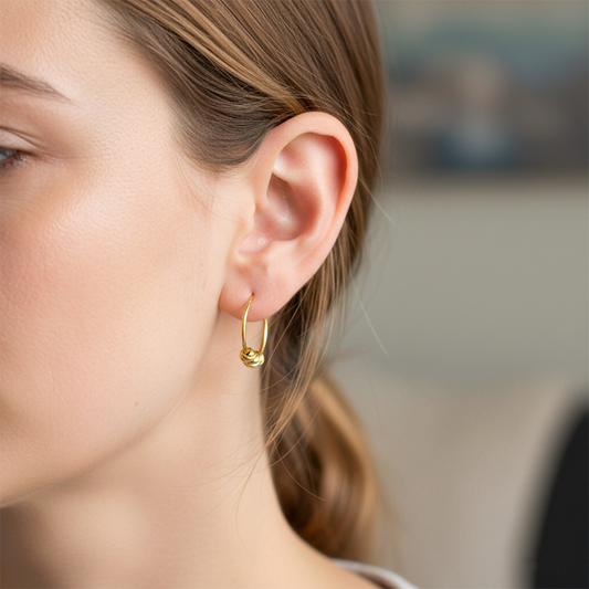 Oreja de modelo usando unos aretes sin fin con esferas en oro amarillo de 18 quilates de Joyería Caracas. 