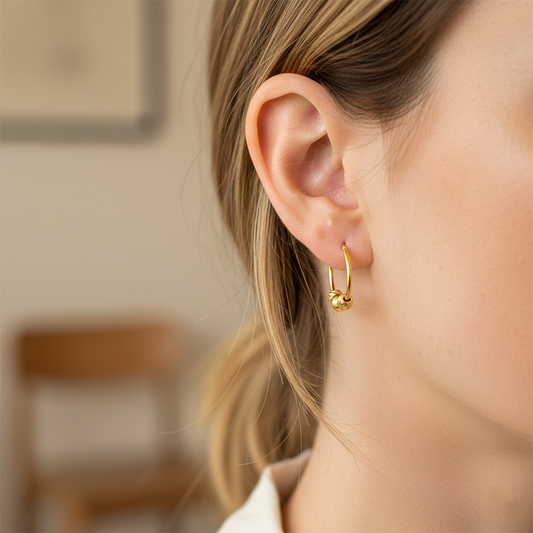 Oreja de modelo usando unos aretes sin fin en oro amarillo de 18 quilates con 3 esferas en oro amarillo de Joyería Caracas. 