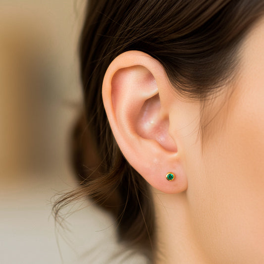 Oreja de modelo usando un topito en oro amarillo de 18 quilates con Esmeralda de Joyería Caracas. 