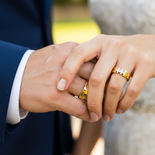 Manos de una pareja usando unas argollas de matrimonio en oro amarillo de 18 quilates con cristales de Joyería Caracas. 