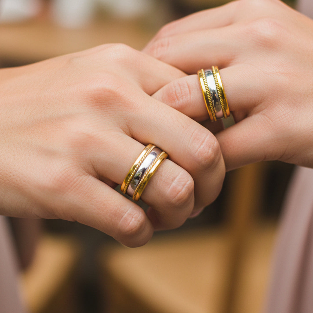 Manos de pareja en matrimonio usando unas argollas de matrimonio con diseño entorchado en oro amarillo y blanco de 18 quilates de Joyería Caracas. 