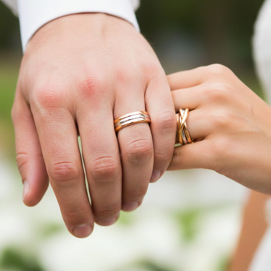 Manos de una pareja usando unas argollas de matrimonio de 3 oros de 18 quilates de Joyería Caracas. 