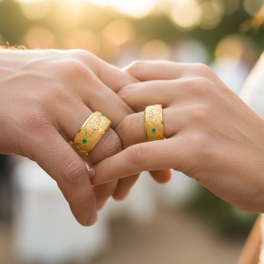 Mano de pareja en matrimonio usando unas argollas de matrimonio en oro amarillo de 18 quilates con cristales verdes de Joyería Caracas. 