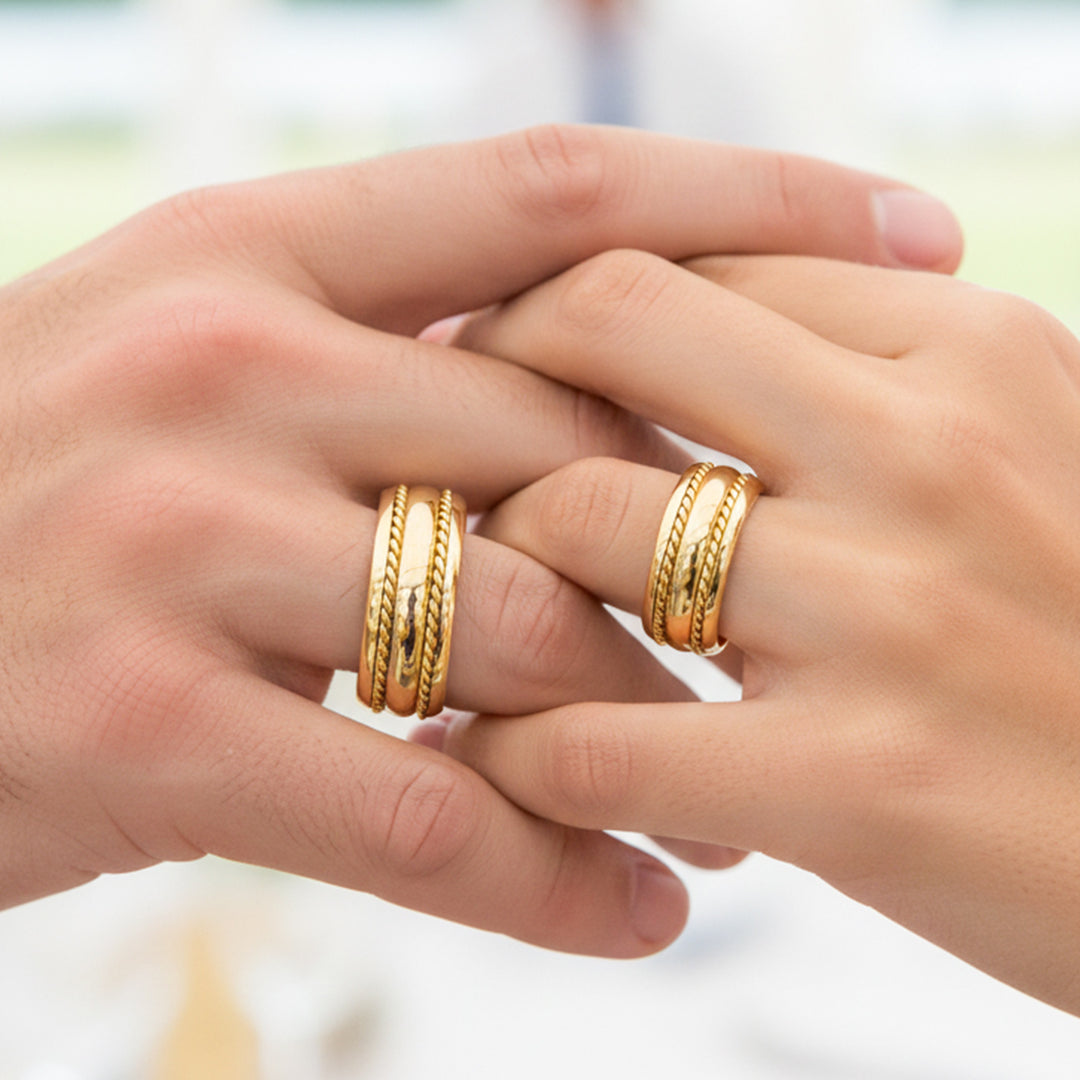Manos de una pareja usando unas argollas de matrimonio en oro amarillo de 18 quilates de Joyería Caracas. 