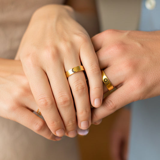 Mano de pareja en matrimonio usando unas argollas en oro amarillo de 18 quilates con grabado en el frente del Sol y Luna de Joyería Caracas. 