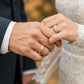 Mano de pareja en matrimonio usando unas argollas en oro amarillo y blanco de 18 quilates con Rubí de Joyería Caracas. 