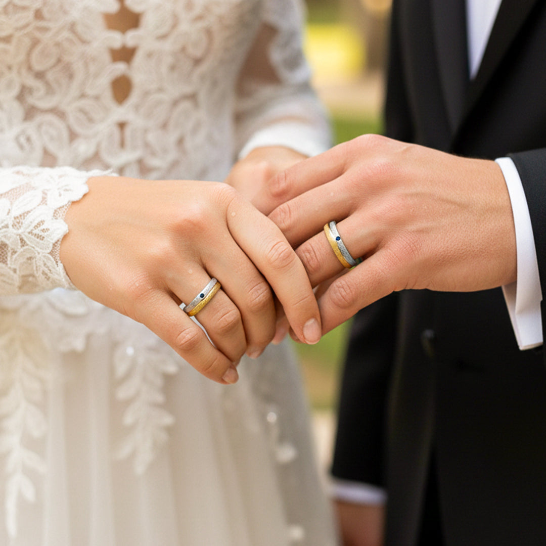 Mano de pareja en matrimonio usando unas argollas en oro amarillo y blanco de 18 quilates con Zafiro de Joyería Caracas. 