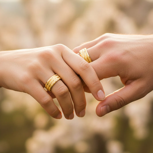 Mano de pareja usando unas argollas en matrimonio facetadas en oro amarillo de 18 quilates de Joyería Caracas. 