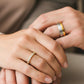 Manos de pareja en matrimonio usando unas argollas en oro amarillo y blanco de 18 quilates con cristales de Joyería Caracas. 