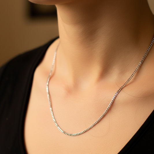 Cuello de mujer usando una cadena en tejido cubana seguida en oro blanco de 18 quilates de Joyería Caracas. 