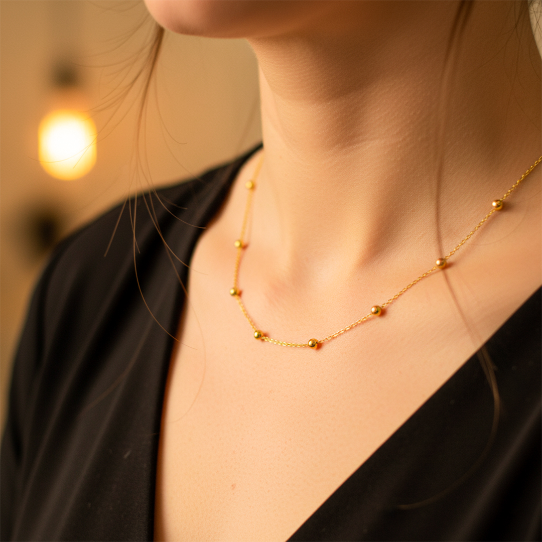 Cuello de mujer usando una cadena con esferas en oro amarillo de 18 quilates de Joyería Caracas. 