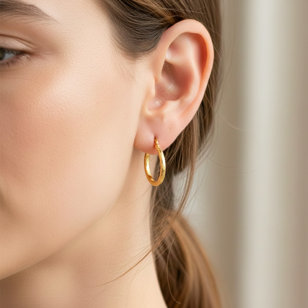 Oreja de modelo usando unas candongas tubo en oro amarillo de 18 quilates de Joyería Caracas. 