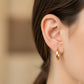 Oreja de modelo usando unas candongas en oro bicolor de 18 quilates de Joyería Caracas. 