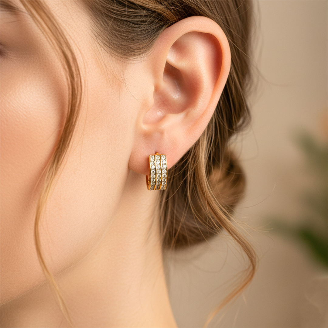 Oreja de modelo usando unas candongas huggies en oro amarillo de 18 quilates con cristales de Joyería Caracas.