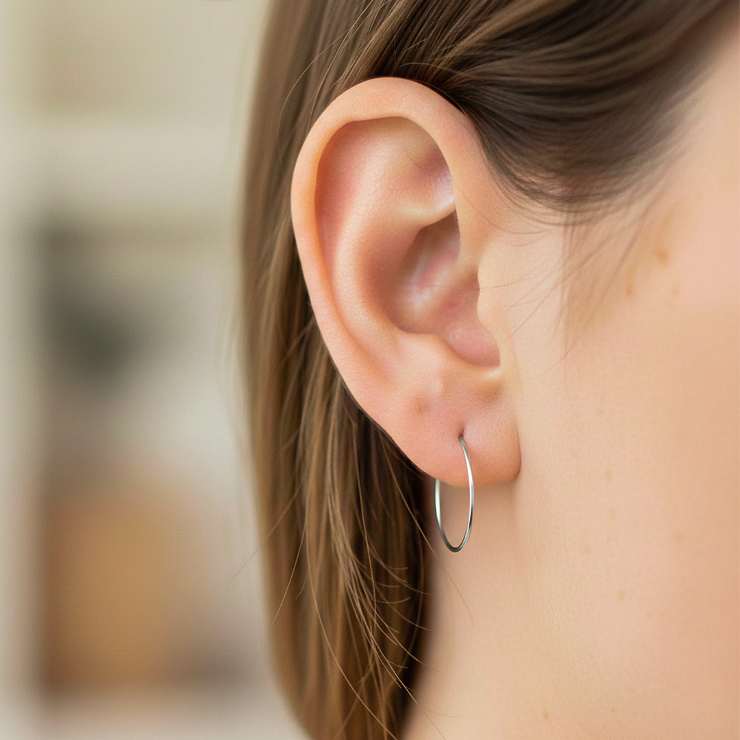 Oreja de modelo usando unas candongas sin fin en oro blanco de 18 quilates de Joyería Caracas. 