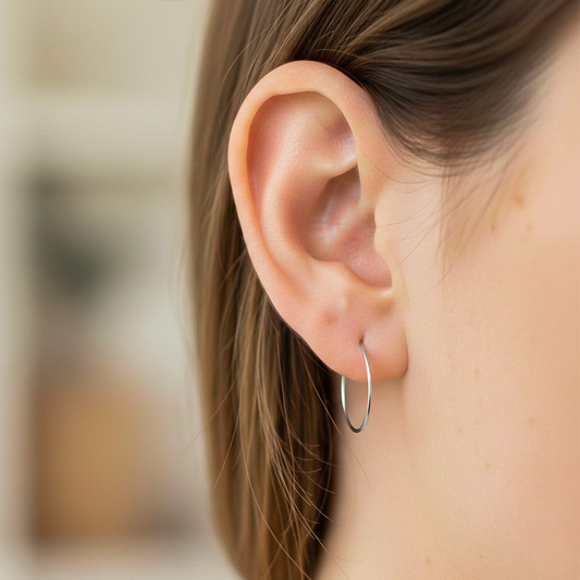 Oreja de modelo usando unas candongas sin fin en oro blanco de 18 quilates de Joyería Caracas. 