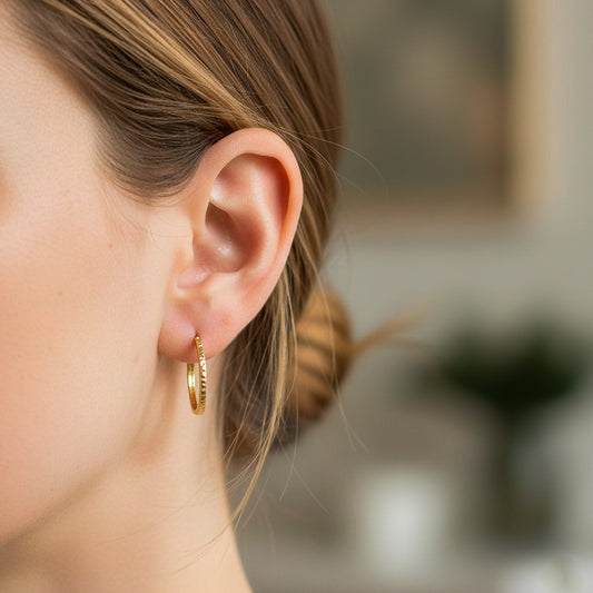 Oreja de modelo usando unas candongas martilladas en oro amarillo de 18 quilates de Joyería Caracas. 