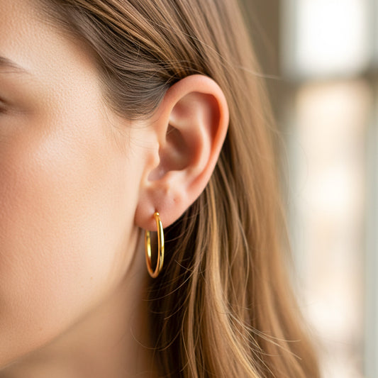 Oreja de modelo usando unas candongas medio tubo en oro amarillo de 18 quilates de Joyería Caracas.