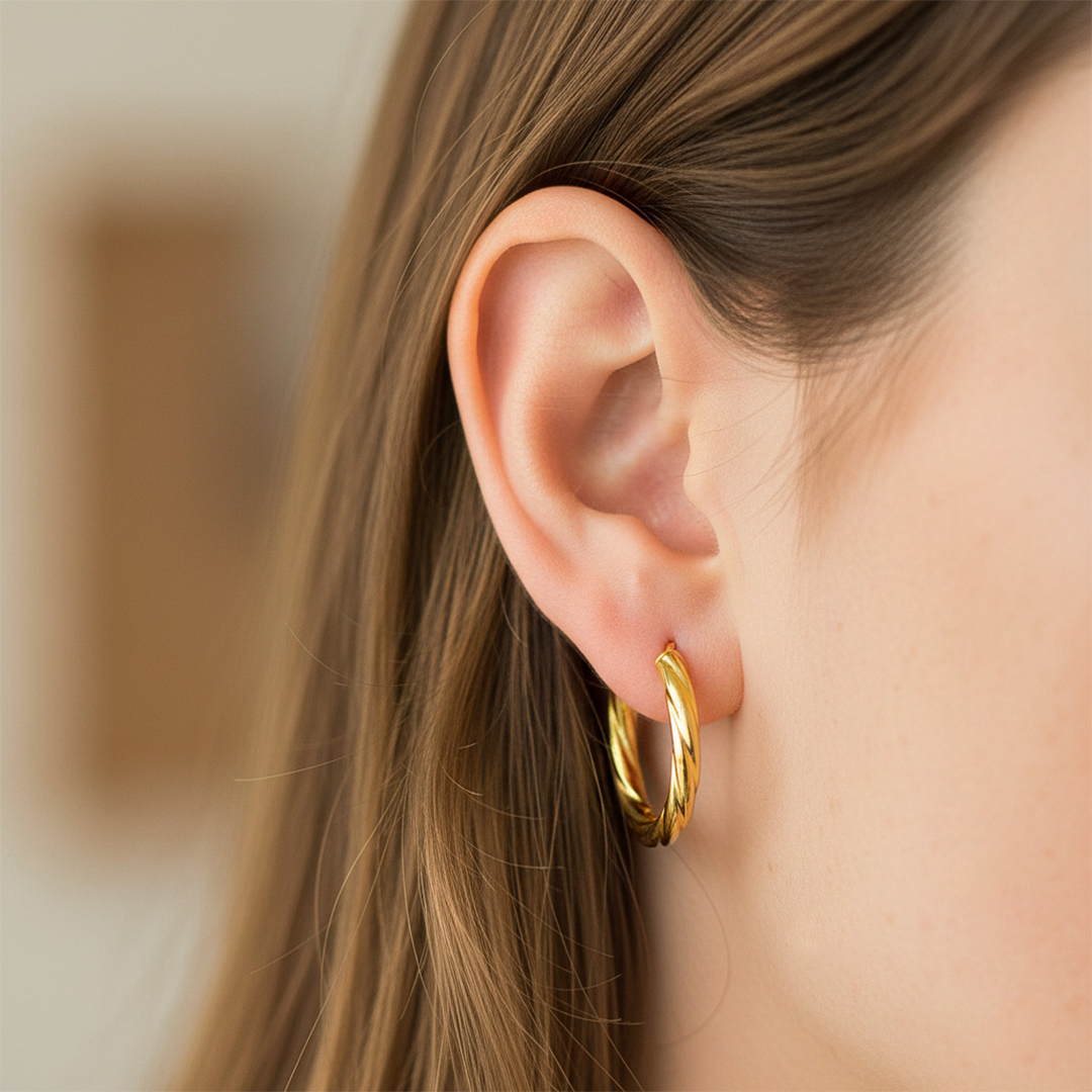 Oreja de modelo usando unas candongas melcocha en oro amarillo de 18 quilates de Joyería Caracas. 