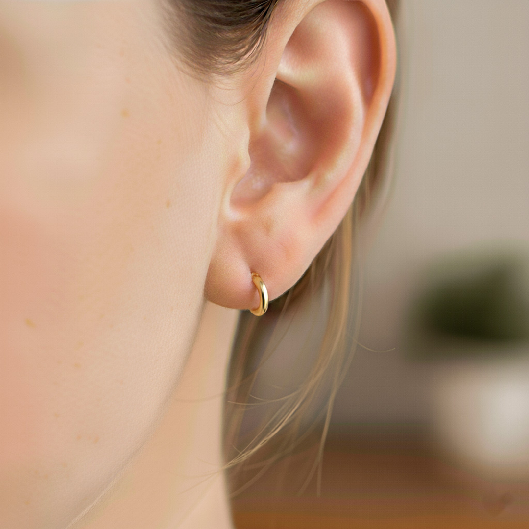 Oreja de modelo usando unas candongas sin fin en oro amarillo de 18 quilates de Joyería Caracas. 