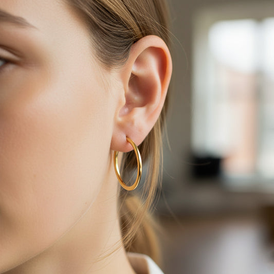 Oreja de modelo usando unas candongas sin fin en oro amarillo de 18 quilates de Joyería Caracas. 