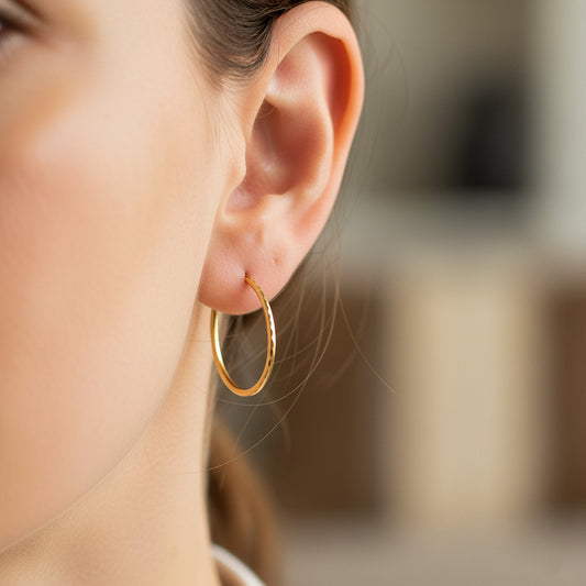 Oreja de modelo usando unas candongas sin fin diamantadas en oro amarillo de 18 quilates de Joyería Caracas. 