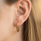 Oreja de modelo usando unas candongas cuadradas en oro amarillo de 18 quilates de Joyería Caracas. 