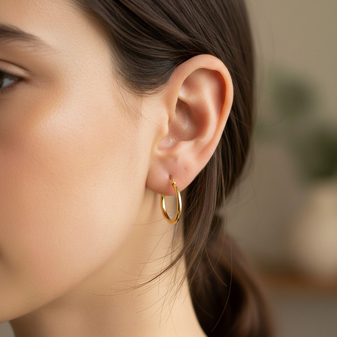 Oreja de modelo usando unas candongas de tubo clásicas en oro amarillo de 18 quilates de Joyería Caracas. 