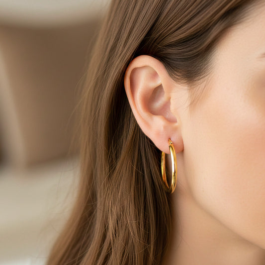 Oreja de modelo usando unas candongas tubo en oro amarillo de 18 quilates de Joyería Caracas.