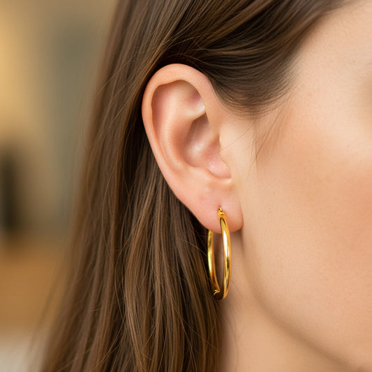 Oreja de modelo usando unas candongas tubo lisas clásicas en oro amarillo de 18 quilates de Joyería Caracas. 