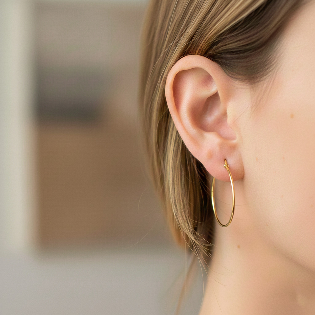 Oreja de modelo usando unas candongas tubo clásicas en oro amarillo de 18 quilates de Joyería Caracas. 