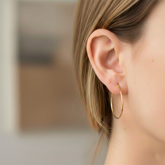 Oreja de modelo usando unas candongas tubo clásicas en oro amarillo de 18 quilates de Joyería Caracas. 