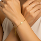 Mano de mujer usando una pulsera denario con esferas lisas en oro amarillo de 18 quilates de Joyería Caracas. 