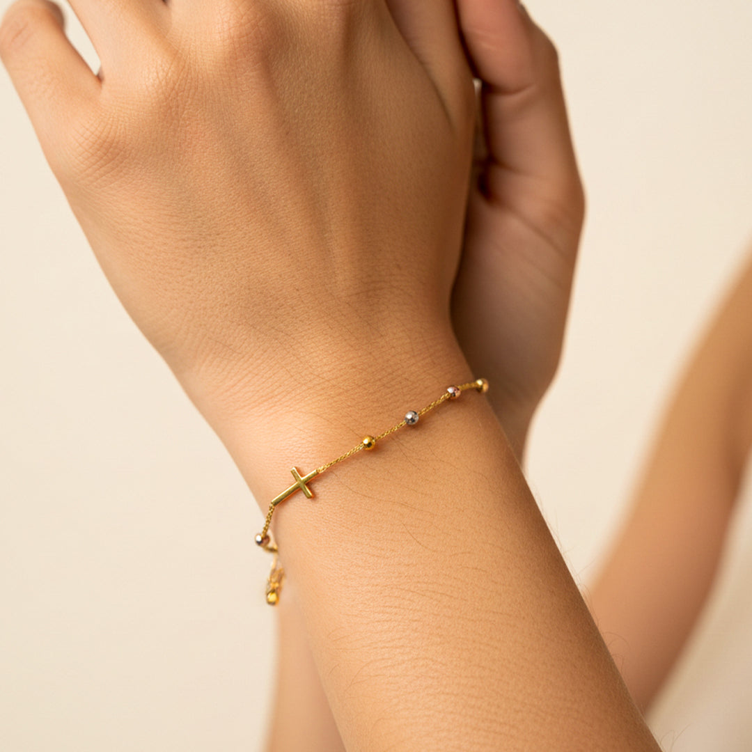 Mano de mujer usando una pulsera denario con esferas facetadas en oro amarillo, blanco y rosa de 18 quilates de Joyería Caracas. 