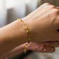 Mano de mujer usando una pulsera denario con esferas facetadas, dije de Virgen y Cruz en oro amarillo de 18 quilates de Joyería Caracas. 