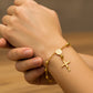 Mano de mujer usando una pulsera denario milagrosa en oro amarillo de 18 quilates de Joyería Caracas. 