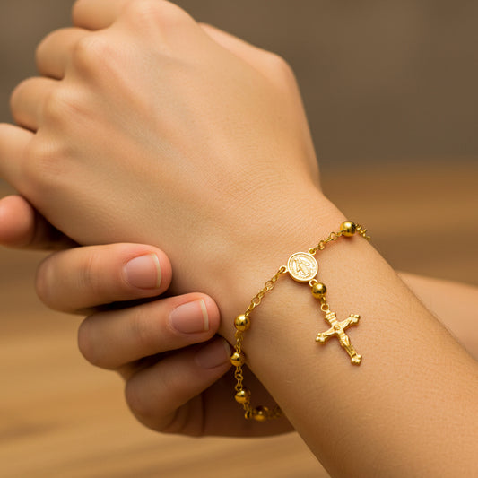 Mano de mujer usando una pulsera denario milagrosa en oro amarillo de 18 quilates de Joyería Caracas. 