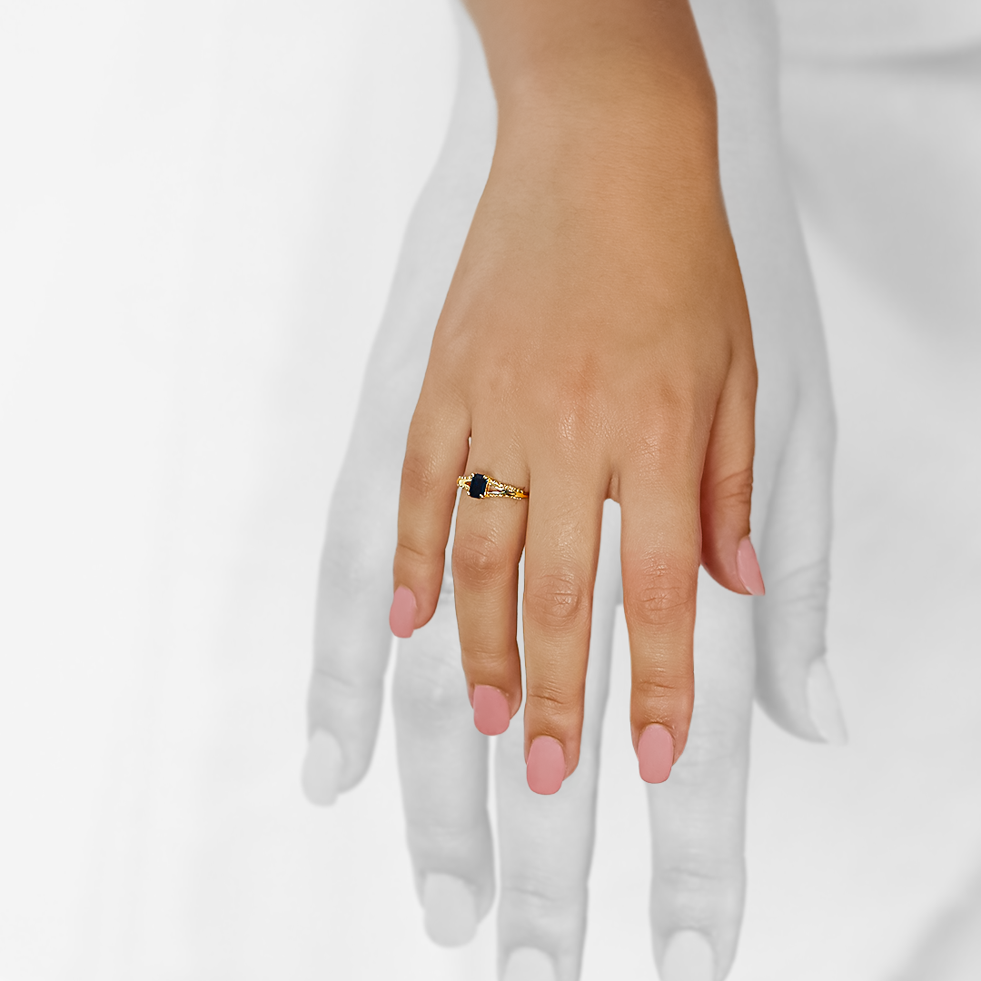Mano de mujer con anillo en oro amarillo de 18 quilates con zafiro de color azul y 20 diamantes de color blanco, hecho en Joyería Caracas. 