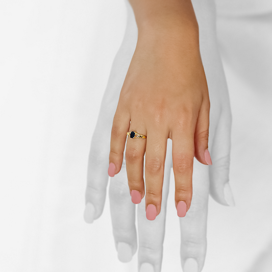 Mano de mujer con anillo en oro amarillo de 18 quilates con zafiro de color azul y 20 diamantes de color blanco, hecho en Joyería Caracas. 