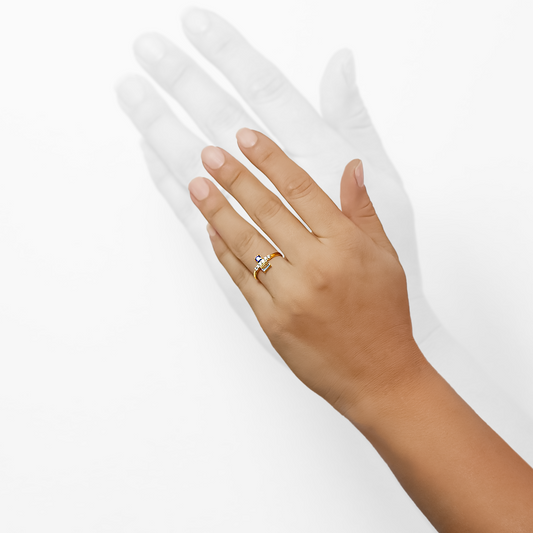 Mano de mujer con anillo en oro amarillo de 18 quilates, zafiro de color azul, topacio de color celeste y 6 diamantes de color blanco, hecho en Joyería Caracas. 